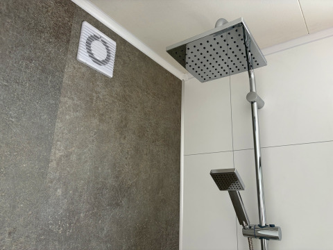 Douche moderne avec pommeau large et ventilation murale au Forest Lodge, parc Krieghuusbelten, Pays-Bas.