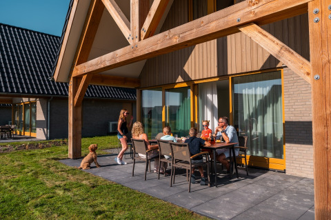 Famiglia si gode un pasto all’aperto alla Duinvilla 8 di EuroParcs Cadzand-Bad, Paesi Bassi, sotto il sole.