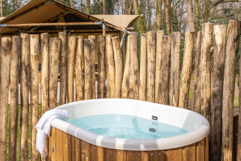 Vasca da bagno esterna davanti a una tenda safari a De Bos Escape, Gooise Heide, Paesi Bassi, recintata in legno.