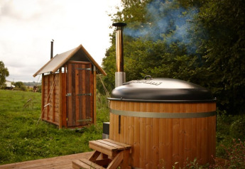 Tente lodge safari avec douche chaude privée près de la tente et bain nordique dans un cadre verdoyant.