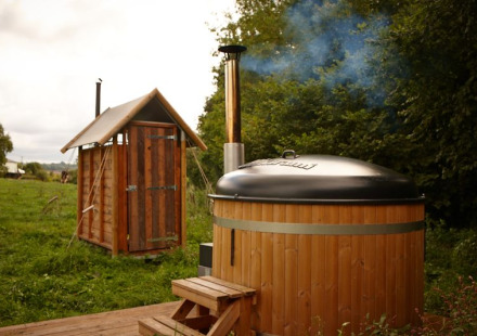 Safaritent cottage met privé warme douche naast de tent en hottub in een groene, natuurlijke omgeving.