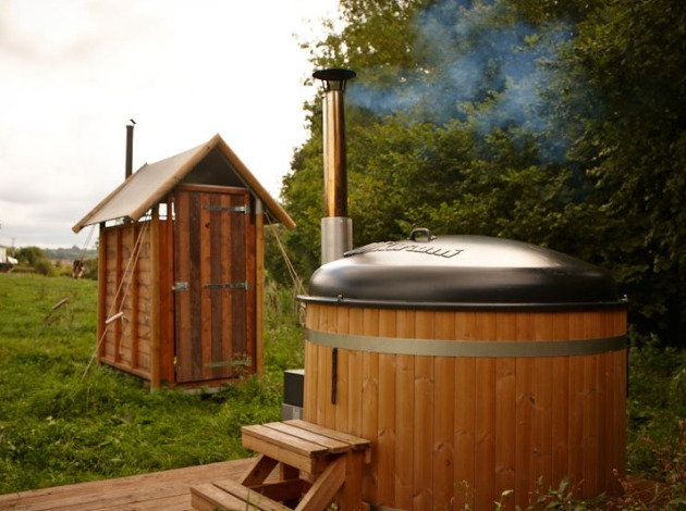 Safaritent cottage met privé warme douche naast de tent en hottub in een groene, natuurlijke omgeving.