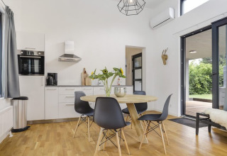 Moderne Küche und Essbereich der Boslodge Plus mit großen Fenstern und Zugang zur Terrasse.