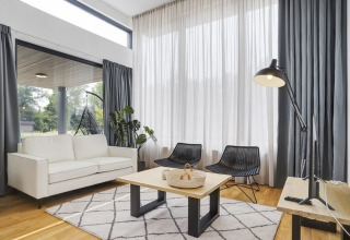 Salon moderne de Boslodge Plus met Hottub, grands rideaux, canapé blanc et chaises noires aux Pays-Bas.