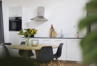 Cocina moderna y comedor con girasoles, sillas negras y elegante decoración en una cabaña.