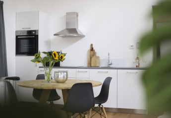 Cocina moderna y comedor con girasoles, sillas negras y elegante decoración en una cabaña.
