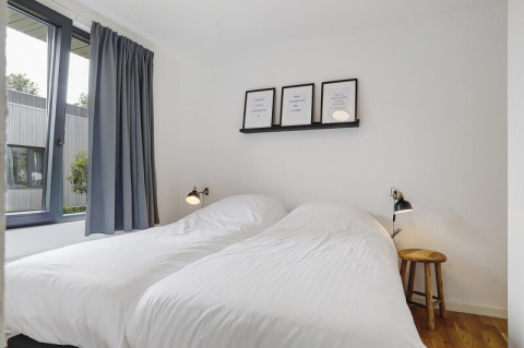Dormitorio moderno en Boslodge Plus met Hottub, centro vacacional 't Schuttenbelt, Países Bajos, con camas gemelas.