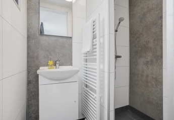 Moderne badkamer met douche, witte wastafel, spiegel en handdoekradiator in Boslodge Plus met Hottub.