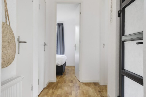 Luminoso pasillo con suelo de madera en Boslodge Plus, con vista al dormitorio en 't Schuttenbelt, Países Bajos.