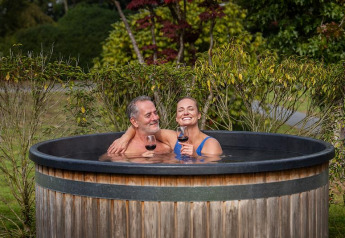 Stel geniet van wijn in een hottub bij Boslodge Plus met Hottub, Holiday center 't Schuttenbelt, Nederland.