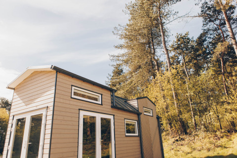 Lille træhus kaldet Koya Tiny Loft beliggende ved Wilsumer Berge, omgivet af grønne træer i Tyskland.