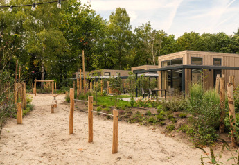 Blick auf das Tiny House Rosendael mit Whirlpool im Veluwe Park de Bosgraaf, umgeben von Natur und Sandweg.