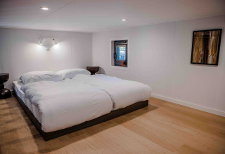 Sfeervolle slaapkamer met tweepersoonsbed in tiny house Rosendael op Veluwe park de Bosgraaf in Nederland.