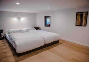 Sfeervolle slaapkamer met tweepersoonsbed in tiny house Rosendael op Veluwe park de Bosgraaf in Nederland.