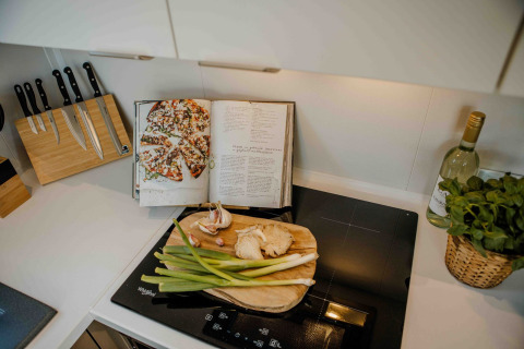 Keukenblad met snijplank, lente-ui en kookboek in tiny house Rosendael met hottub op Veluwe park de Bosgraaf.