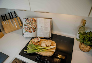 Keukenblad met snijplank, lente-ui en kookboek in tiny house Rosendael met hottub op Veluwe park de Bosgraaf.