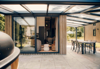 Modernes Tiny House Rosendael mit überdachter Terrasse und Sitzgruppe im Veluwe park de Bosgraaf, Niederlande.