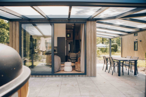 Moderne tiny house Rosendael met overdekt terras en tuinmeubilair in Veluwe park de Bosgraaf, Nederland.