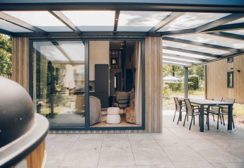 Moderne tiny house Rosendael met overdekt terras en tuinmeubilair in Veluwe park de Bosgraaf, Nederland.