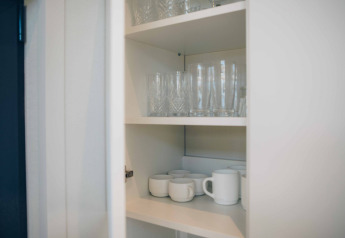 Een kast in het tiny house Rosendael bij Veluwe park de Bosgraaf, Nederland, met glazen en mokken.