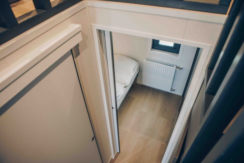 Uitzicht op een kleine slaapkamer in tiny house Rosendael met hottub in Veluwe park de Bosgraaf, Nederland.