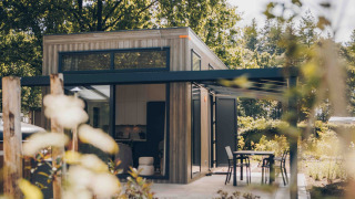 Moderne tiny house Rosendael met overdekt terras en tuin, omringd door bomen en veel groen.