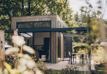 Moderne tiny house Rosendael met overdekt terras en tuin, omringd door bomen en veel groen.