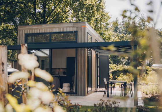 Moderne tiny house Rosendael met overdekt terras en tuin, omringd door bomen en veel groen.