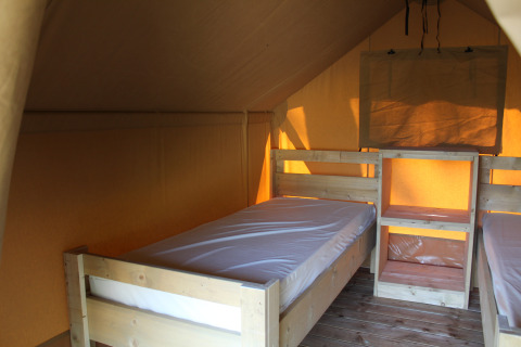 Innenansicht eines Safari-Zeltes mit Holzbetten und Regalen auf dem Campingplatz La Colline in Belgien.