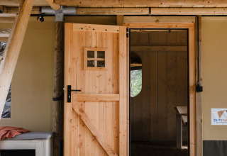 Ingang van safaritent De Bosvilla op de Gooise Heide in Nederland met openstaande houten deur.