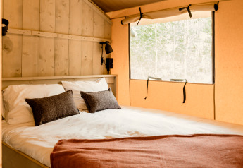 Cozy bedroom with large window in safari tent ‘De Bosvilla’ at Gooise Heide in the Netherlands.