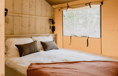 Knusse slaapkamer met tweepersoonsbed in safaritent ‘De Bosvilla’ op de Gooise Heide in Nederland.