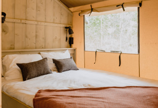 Knusse slaapkamer met tweepersoonsbed in safaritent ‘De Bosvilla’ op de Gooise Heide in Nederland.