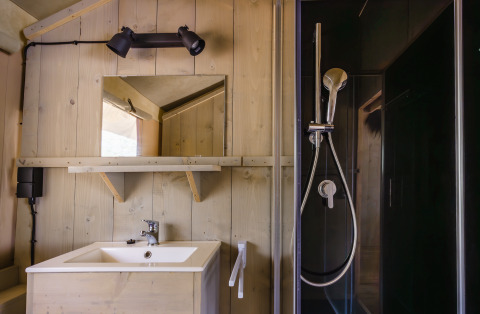 Badkamer in safaritent 'De Bosvilla' op de Gooise Heide in Nederland, met douche, wastafel en spiegel.