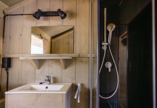 Badkamer in safaritent 'De Bosvilla' op de Gooise Heide in Nederland, met douche, wastafel en spiegel.