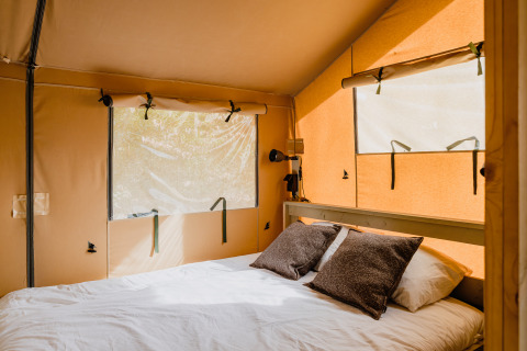 Interieur van safaritent ‘De Bosvilla’ met comfortabel bed op Gooise Heide in Nederland.