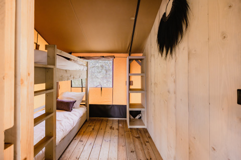 Interieur van safaritent De Bosvilla op Gooise Heide, Nederland met stapelbed en houten vloer.