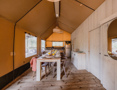 Interieur van safaritent ‘De Bosvilla’ op Gooise Heide in Nederland met eettafel en keukenruimte.