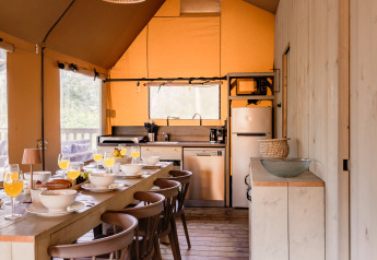 Cozy kitchen and dining area in the safari tent De Bosvilla at Gooise Heide, Netherlands, set for breakfast.