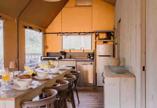 Gezellige keuken en eethoek in safaritent De Bosvilla op de Gooise Heide, Nederland, gedekt voor ontbijt.
