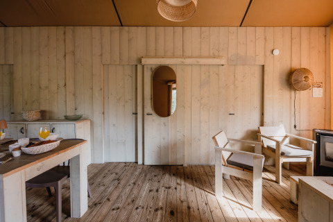 Interieur van safaritent De Bosvilla op de Gooise Heide, Nederland, met houten meubels en vloer.
