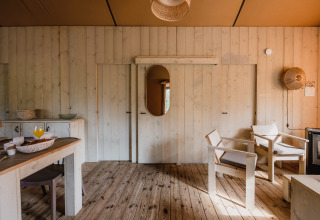 Interieur van safaritent De Bosvilla op de Gooise Heide, Nederland, met houten meubels en vloer.