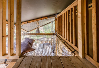 Interior of the safari tent 'De Bosvilla' at Gooise Heide, Netherlands, featuring net space and pillows.