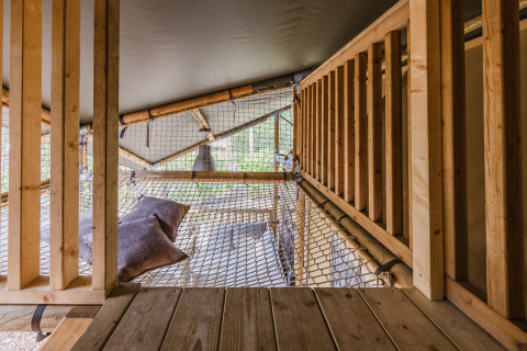 Interieur van safaritent 'De Bosvilla' op Gooise Heide in Nederland met net en kussens om te ontspannen.