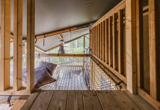 Interieur van safaritent 'De Bosvilla' op Gooise Heide in Nederland met net en kussens om te ontspannen.