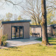 Chalets glamping modernes avec bardage en bois et terrasse, entourés d’arbres et de verdure.