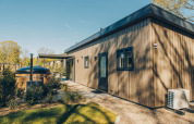 Esterno del lodge Loevestein Comfort al parco Veluwe de Bosgraaf nei Paesi Bassi, con terrazza e vasca idromassaggio.