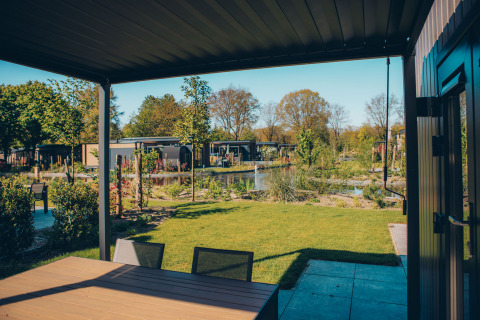 Vista dalla terrazza della Loevestein Comfort lodge a Veluwe park de Bosgraaf, Paesi Bassi, su stagno e giardino.