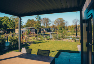 Vista dalla terrazza della Loevestein Comfort lodge a Veluwe park de Bosgraaf, Paesi Bassi, su stagno e giardino.