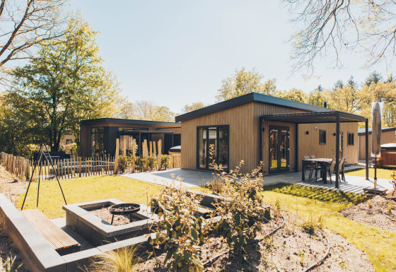Loevestein Deluxe lodge with hot tub, stylish patio, fire pit, and serene garden in a forest setting.
